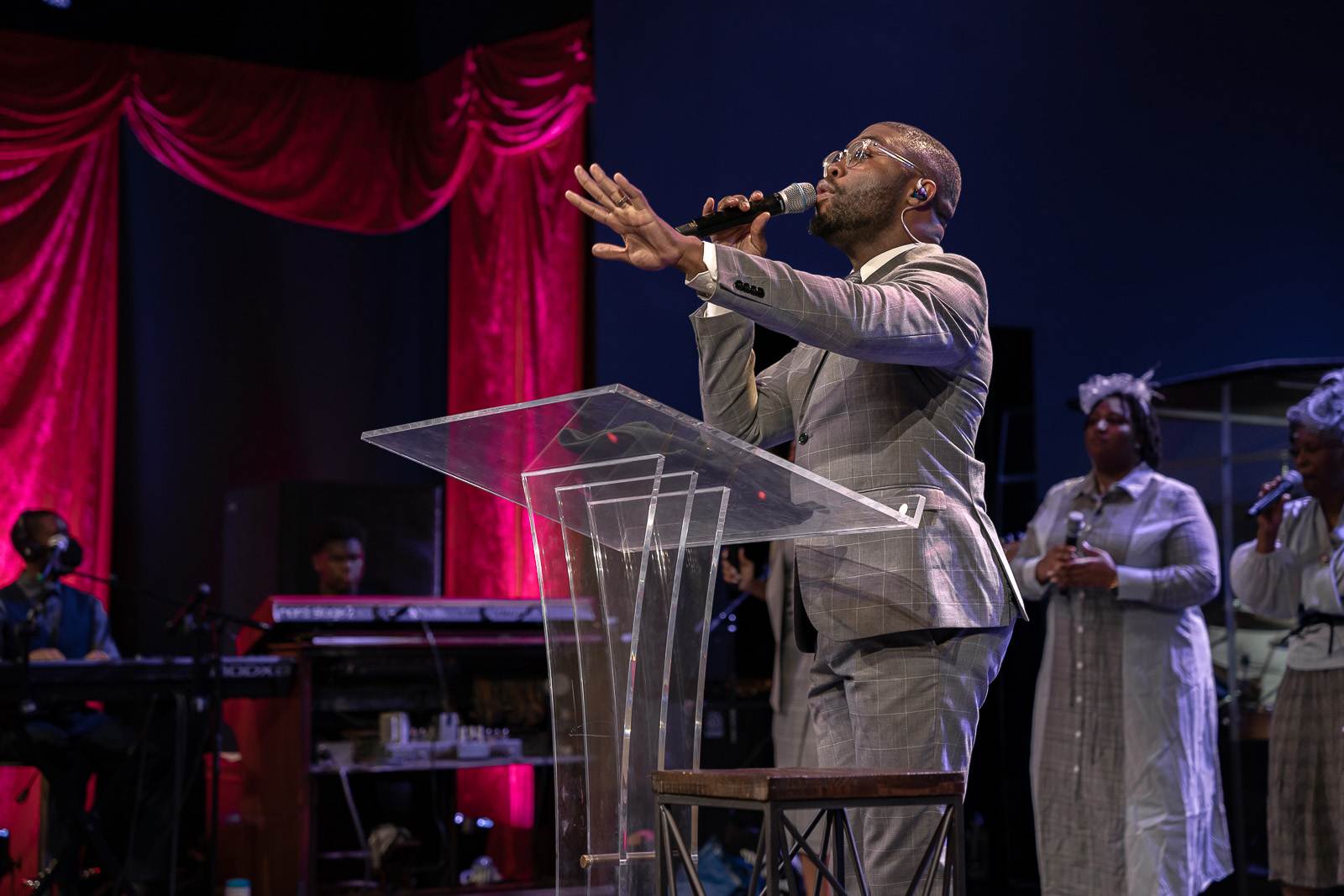 A man in a suit is singing into a microphone at church.