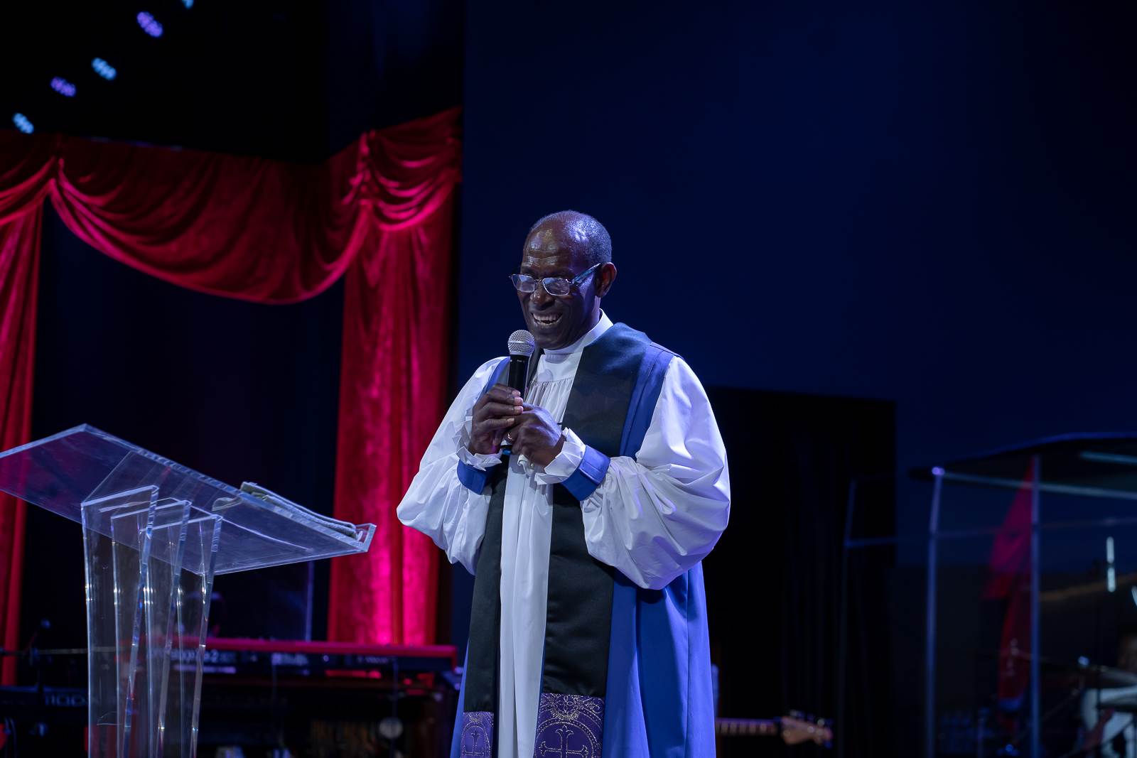 An apostolic man in a priest's robe standing at a church podium.