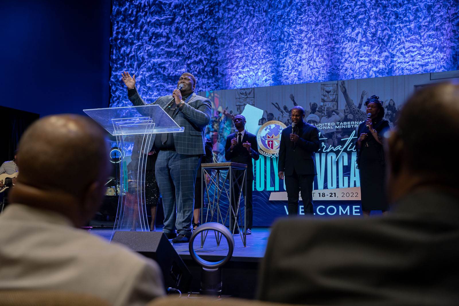 A man is delivering an apostolic speech at a church gathering.