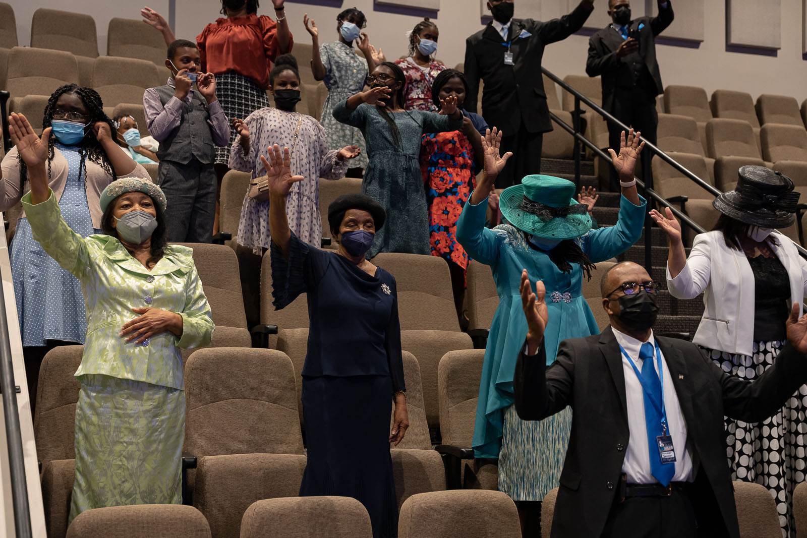 A group of apostolic people wearing face masks in an auditorium.