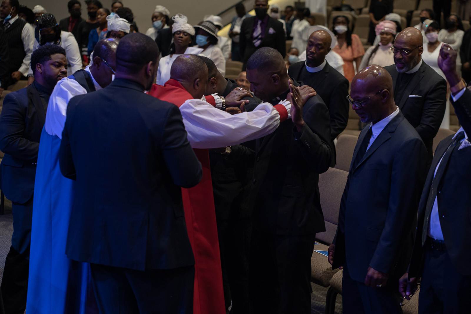 A group of apostolic men in suits and ties standing in a church.